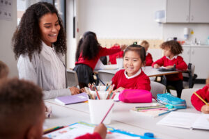 Female,Teacher,And,Chinese,Schoolgirl,Sitting,At,A,Table,In